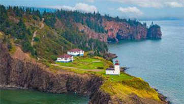 An image of a lighthouse against a backdrop of cliffs and ocean.