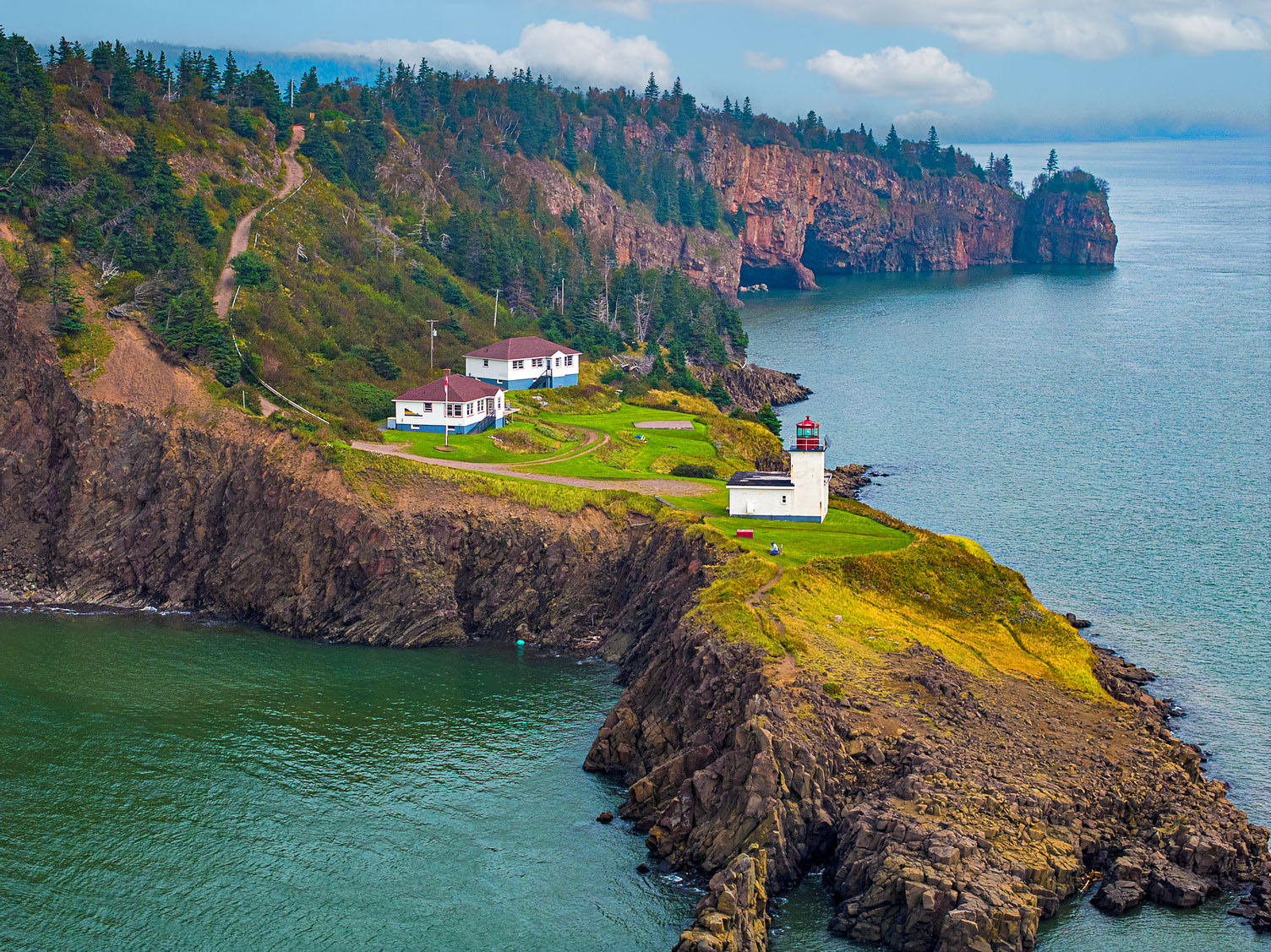 An image of a lighthouse against a backdrop of cliffs and ocean.