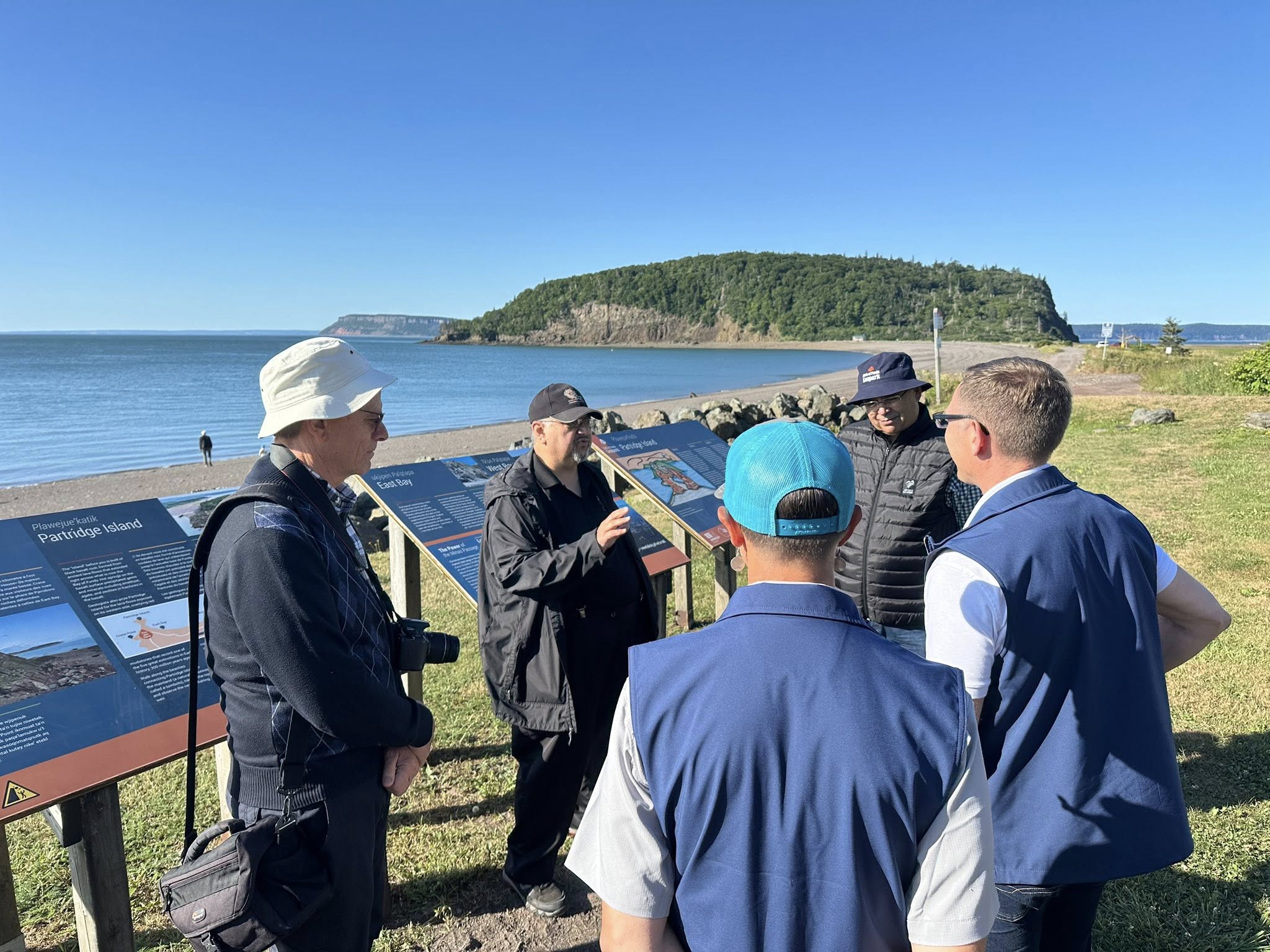 A group of people gather around interpretive signage of Partridge Island near Parrsboro.